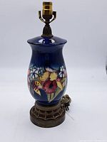 Full view of blue glazed ceramic lamp with floral decoration on brass base
