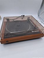 Full view of the entire turntable with dust cover, woodgrain base, and power cord.
