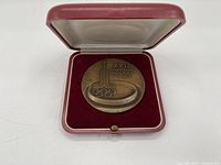 Front view of the bronze medal inside its red velvet-lined presentation case.