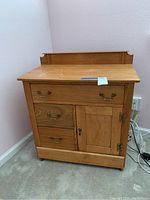 Front view of vintage oak dry sink cabinet showing drawers and door.