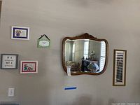 Wall showing oak mirror and five framed wall art pieces.