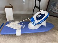 Oreck cordless iron on mini ironing board with charging base nearby.