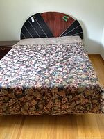 Front view of the full-size bed showing the sunburst semi-circular headboard and floral bedding with beige sheets underneath.