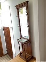 Full front view of oak hall tree showing mirror, marble top, and coat hooks