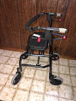 Front angle view showing padded seat, black metal frame, and hand brakes on handles.