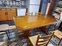 Oak dining table with glass top, shown in a kitchen environment with surrounding chairs not included.