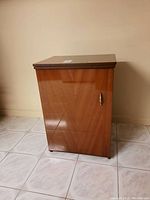 Front view of wooden sewing machine cabinet with closed door and brass handle