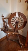 Full view of the antique wooden spinning wheel showing the overall structure, base, legs, and large wheel