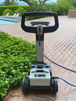 Robotic pool cleaner power supply module mounted on wheeled caddy on brick patio
