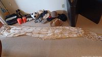Photo of cream fabric hammock extended on floor with assorted hats and gloves in background