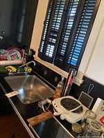 Electric stove top on counter with wooden handles, visible kitchen sink, and other kitchen items around