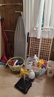 The whole lot showing ironing board, laundry basket with clothes, broom, dustpan, bottles of cleaning supplies, and laundry drying rack.