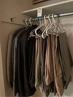 Photo of men's suit jackets and pants hanging on a rack, showing a variety of dark and neutral colors.