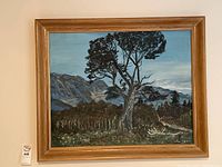 Frontal view of original landscape painting with large central tree and mountainous background, framed in wooden frame with visible wear and imperfections.