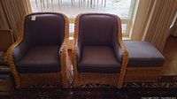 Two rattan armchairs and one matching ottoman, all with dark brown cushions, captured from the front showing overall condition and appearance.