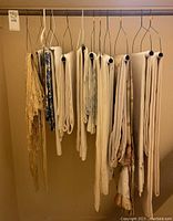 Full view of linens and textiles hanging on individual wire hangers, showing assortment of different linen pieces in neutral tones including woven and plain fabric