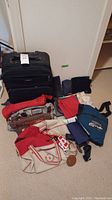 Photo showing various travel bags and supplies including Samsonite rolling suitcase, duffel bags, and backpacks.