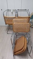Four chairs stacked showing chrome frames and cane backs