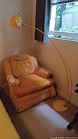 Full view of yellow arc floor lamp near armchair