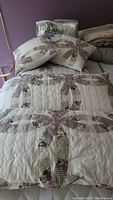 Full view of the king size quilt and two square decorative pillows showing the patchwork floral and green plaid design on cream background.