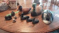 Wide view showing all bird carvings and soapstone sculptures arranged on a wood table.