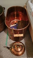 Large oval copper pot showing interior and wooden handles
