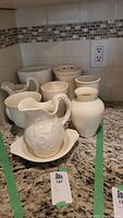 Overall lot displayed on kitchen counter including cream pottery pitcher with bowl, assorted vases and goblets.