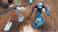 Two eagle decor statues on wooden surface; composite eagle with babies and glass pedestal eagle head