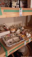 Photo showing shelf with various ceramic items including Easter bunnies, decorative plates, and ceramic jars.