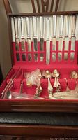 Wooden box lined with red fabric holding 10 cutting knives in top slots and assorted forks and spoons below