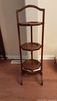 Front view of the 3 tier wooden folding tea tray stand with visible carved octagonal trays and top handle.