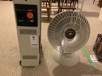Front view of Delonghi electric heater and Heatdish parabolic heater side by side on carpeted floor.