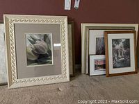 Multiple framed prints on floor against wall showing size and framing styles