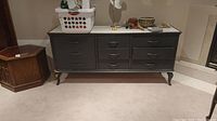 Full view of painted wood cabinet with stone top and six drawers in a basement room.