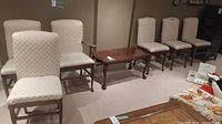Seven chairs shown: six armless with beige geometric fabric on wood legs and one captains chair with arms and same upholstery; visible seam damage on one armless chair.