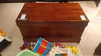 Side/front angled view of chest with surrounding items on floor to indicate size.