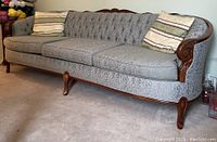 Front view of three cushion sofa with tufted back and carved wood frame