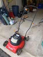 Front right angle view of red and black Homelite electric lawn mower with handlebar and wheels.