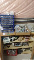 Wide view showing the blue organizer with drawers and shelves below with boxes and parts, including the toilet paper holder and light cover.