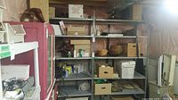 Front view of metal shelving unit with multiple items on shelves, stored in basement area.