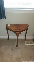 Full view of the wood demi-lune side table showing its shape and leg design.