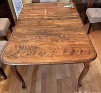 Top view of the wooden dining table showing wood grain and finish with leaf attached.