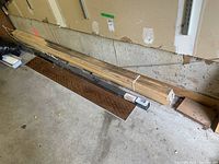 Photo showing bundle of wood pieces on concrete floor including long Medallion fence post package and assorted wood pieces