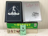 Two collectible card albums placed on top of several vintage and modern storage boxes, showing the titles and condition of the albums and boxes.