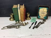Complete view of all lot items: 4 vintage cookbooks, spatula and fork butter utensils, 8 iced tea spoons, old Gem razor, and boxed wooden puzzle