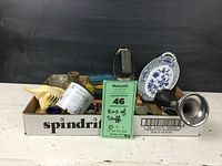 Overview photo of box containing assorted vintage items such as dishes, tins, novelty items, and small containers.