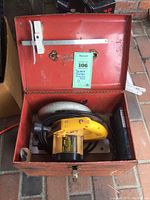 DeWalt DW364 circular saw placed inside a rusty red metal carrying case with latch, case open showing the saw inside.