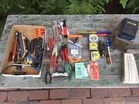 Full layout of all tools on an outdoor bench, showing a variety of hand tools including pliers, a hand plane, measuring tapes, knives, and storage.