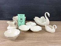 Full set of seven Lenox china pieces including bowls, swan figurines, pitcher, and condiment dish displayed together on wooden surface