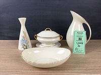 Photo showing all four Lenox pieces: modern white pitcher, decorated vase, covered dish, and oval dish.